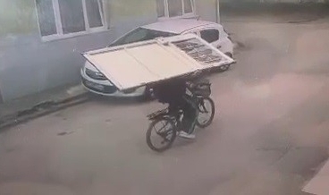 Sırtladığı kapıyı bisikletle böyle taşıdı