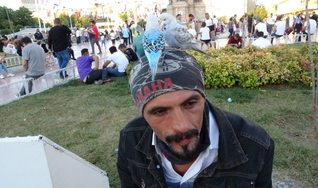 Başında gezdirdiği 3 muhabbet kuşuyla Taksim’de ilgi odağı oldu