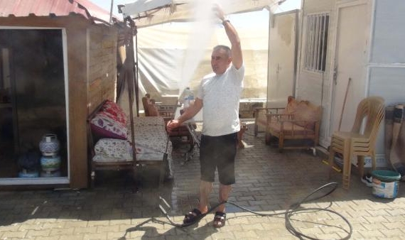 Hatay'da sıcak havalardan bunalan vatandaş çadırların önünde suyla serinledi